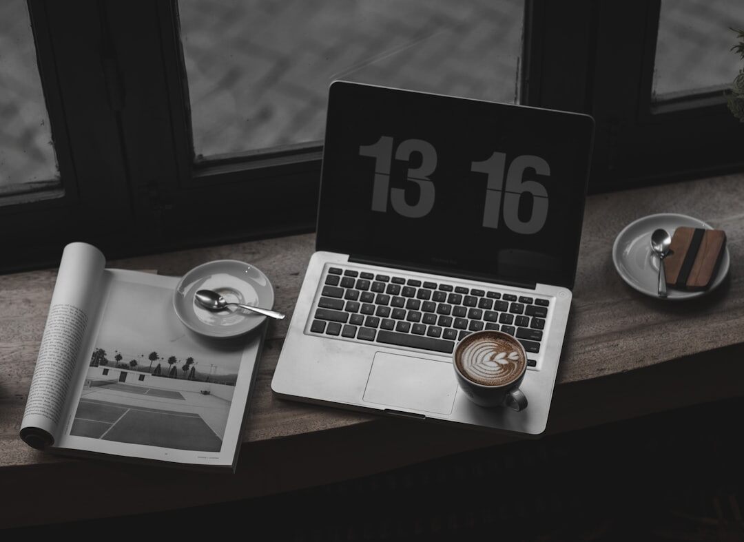 Small newsroom desk with laptop, notebook and coffee cup
